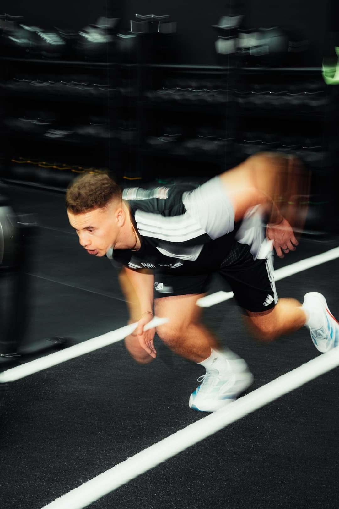 Athlet im Sprint-Antritt auf dunklem Trainingsplatz