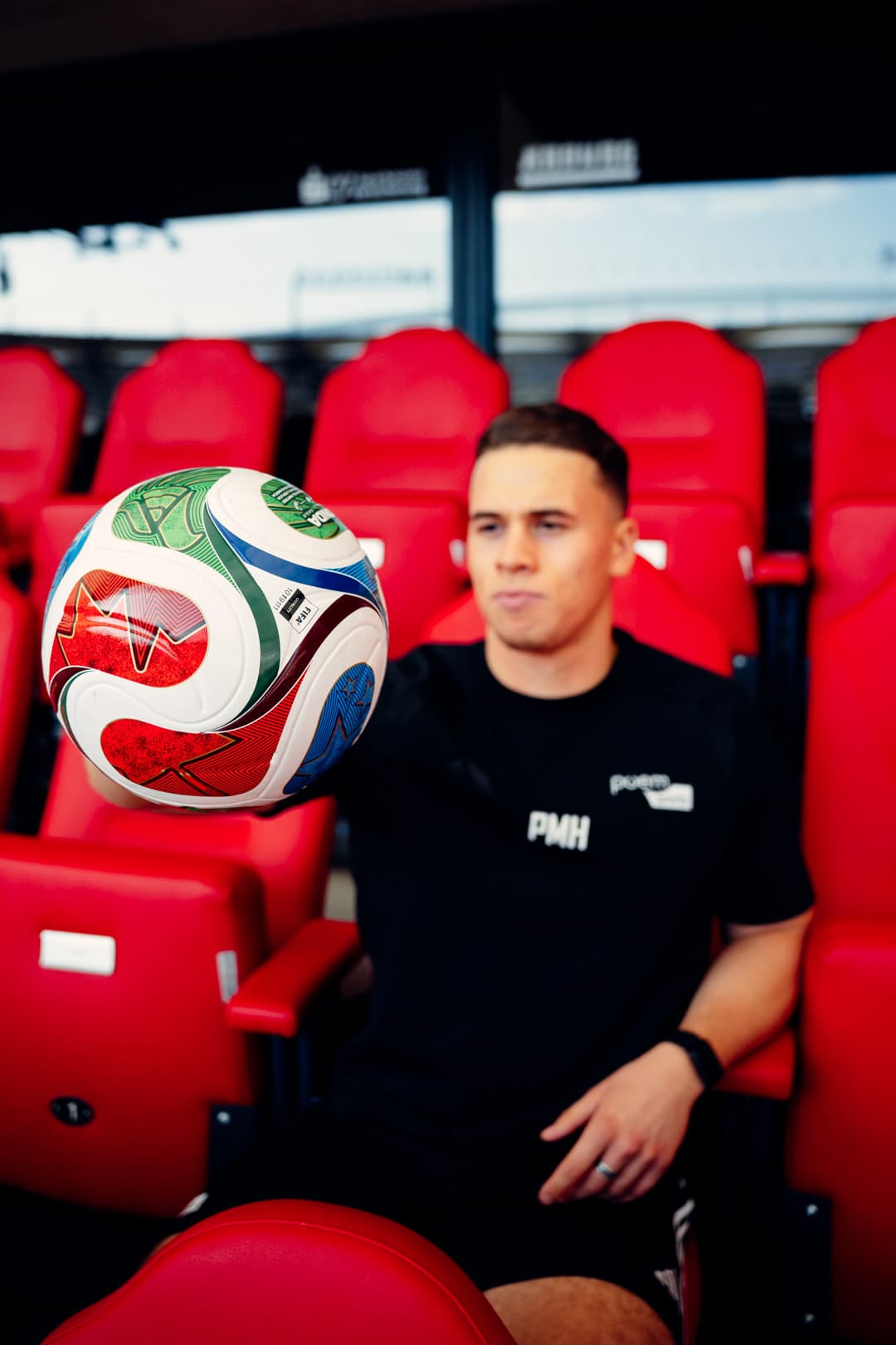 Phil im schwarzen poemsports-Shirt auf den roten Sitzen der MHP Arena, vorne der WM-Spielball